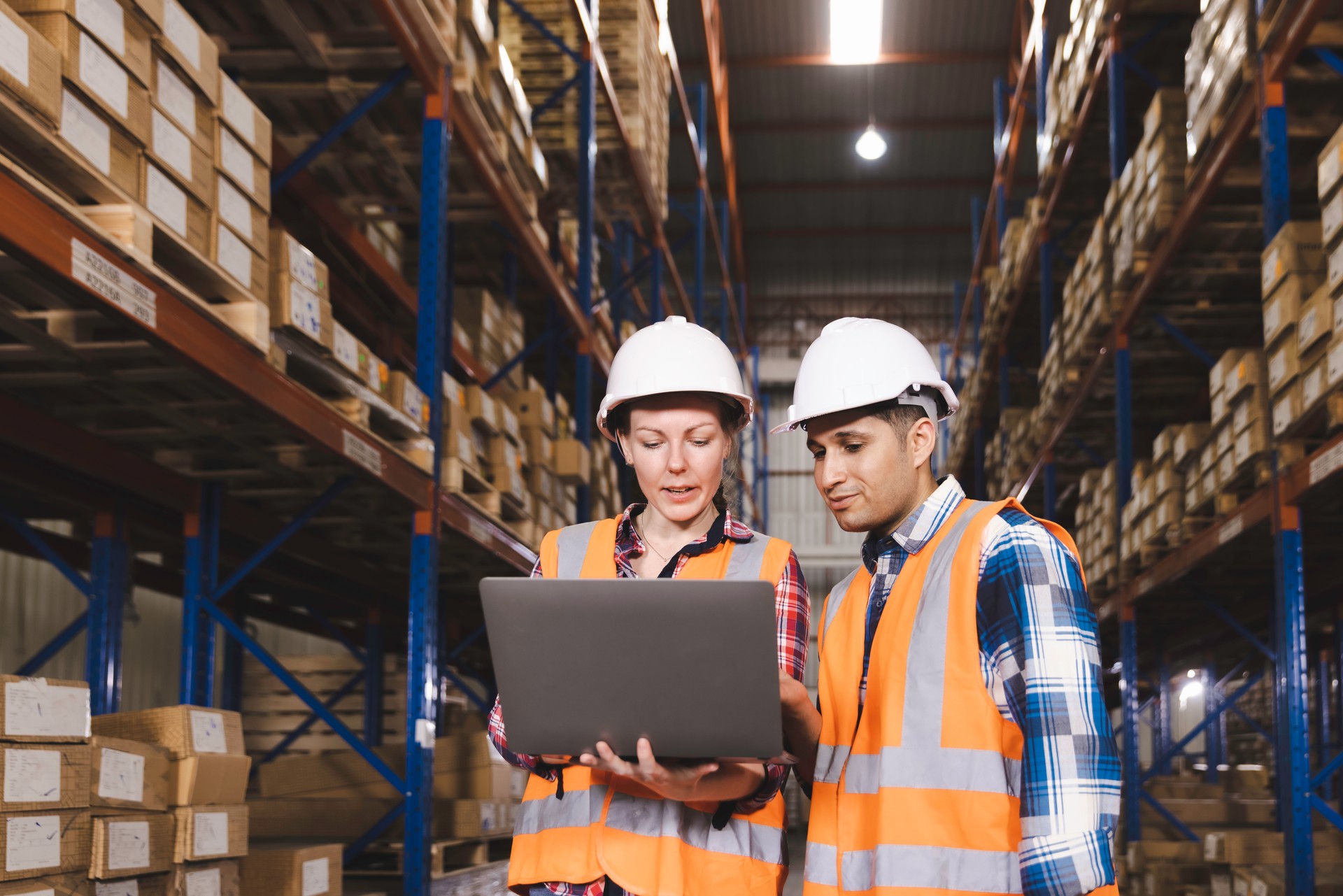 Logistic worker staff colleague in safety suit holding computer laptop working in a warehouse store