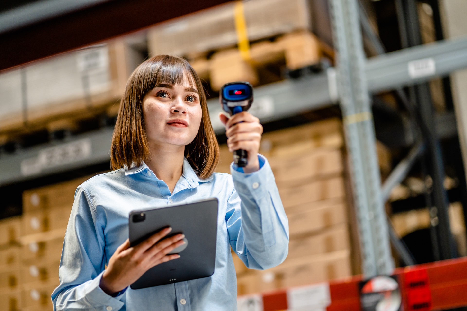 Women worker use scanner to check and scan barcodes of stock inventory on shelves to keep storage in a system, Smart warehouse management system, Supply chain and logistic network technology concept.